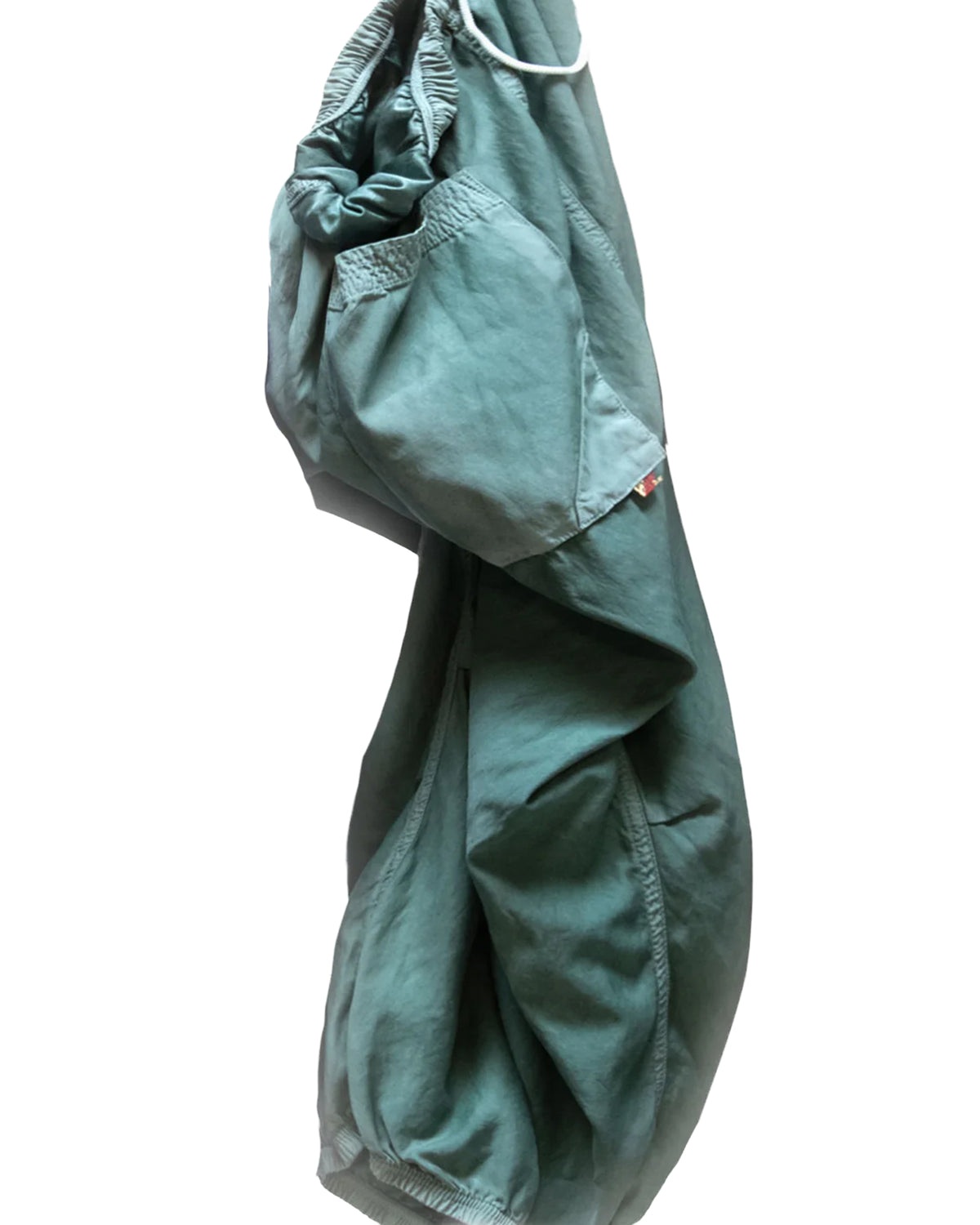 The Matte/Satin Biggy Pant by Free City (sparrow, LLC), featuring an oversized fit with elastic waistband and cuffs, hangs against a white background. The green drawcord pants showcase a relaxed, loose silhouette.