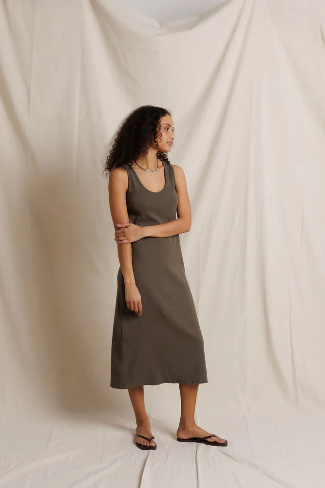 Olive ribbed midi tank dress by Perfectwhitetee, styled with sandals in front of a cream fabric backdrop.