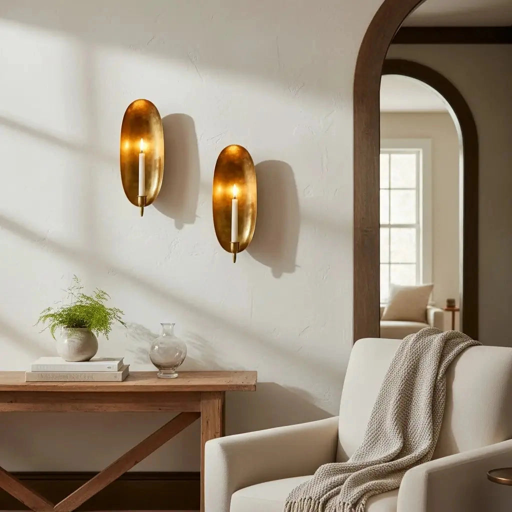 Faire Brass Wall Candle Sconce brings warmth to a bright, airy living room with white accents and an arched doorway.