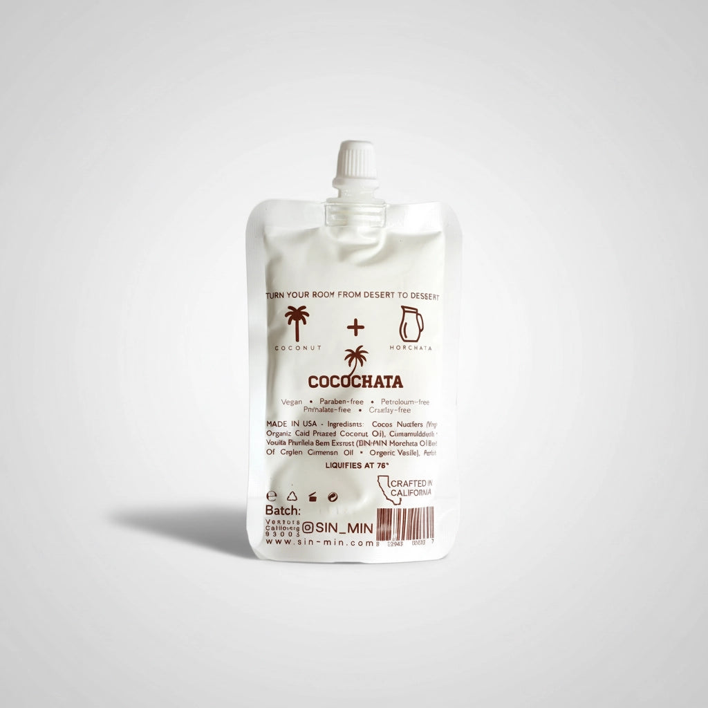 A white pouch labeled "Cocochata Body Beverage" by Faire features coconut and cinnamon icons, a screw cap, and minimalist brown text. This vegan body oil is perfect as a coconut oil moisturizer for sensitive skin.