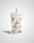 A white pouch labeled "Cocochata Body Beverage" by Faire features coconut and cinnamon icons, a screw cap, and minimalist brown text. This vegan body oil is perfect as a coconut oil moisturizer for sensitive skin.