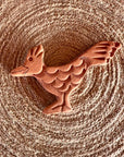 The Faire Brown Sugar Keeper is a handmade, terracotta-colored clay figurine with detailed feather patterns, resting on a woven circular mat, reminiscent of classic ceramic brown sugar keepers.