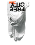 The Flap/Snap AirJump Pant by Free City (sparrow, LLC) features a white unisex satin design with elastic waistband and cuffs, custom sunfade wash, bold black FREECITY print, and an orange graphic, shown upside down on a plain white background.