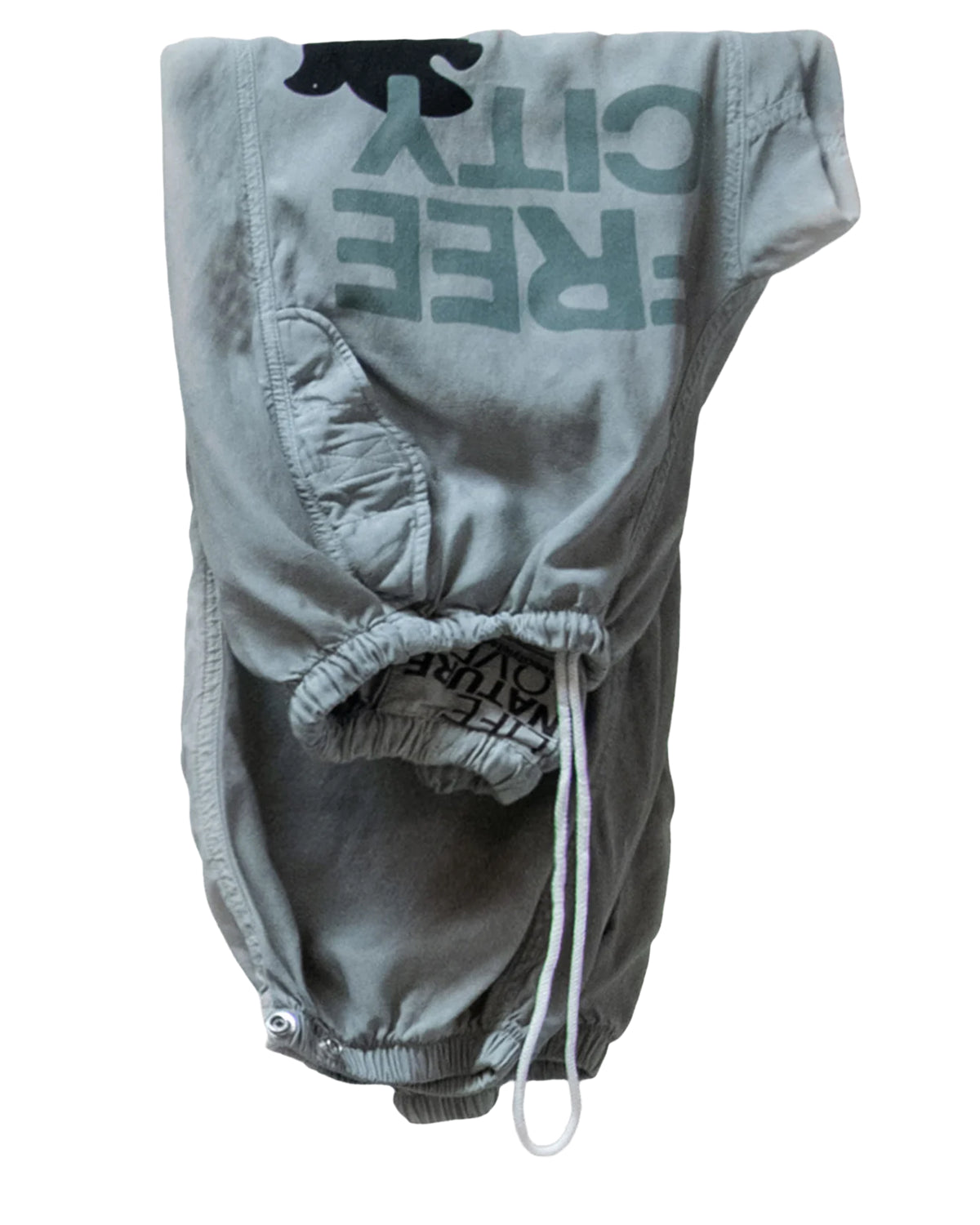 The Flap/Snap AirJump Pant by Free City (sparrow, LLC) features a light gray sunfade wash, drawstring waistband, front pockets, and an upside-down dark green FREECITY print. The shorts are displayed flat on a white background.
