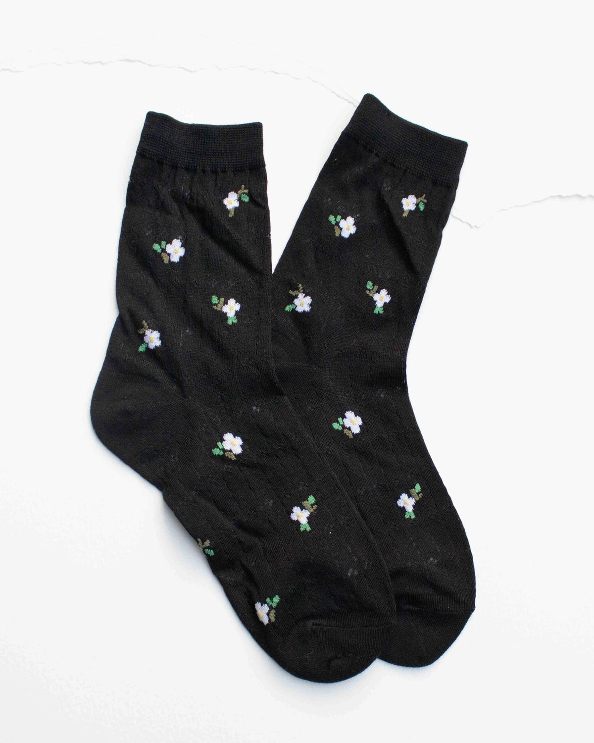 Faire Mini Floral Cotton Socks in black, featuring white and purple flowers with green leaves, are laid flat on a white background. Made from breathable cotton, these feminine socks offer all-day comfort.