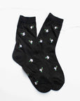 Faire Mini Floral Cotton Socks in black, featuring white and purple flowers with green leaves, are laid flat on a white background. Made from breathable cotton, these feminine socks offer all-day comfort.