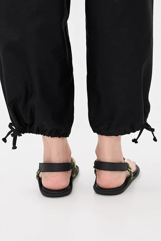 Black adjustable Flowze FLO sandals paired with drawstring pants, back view on a white background.