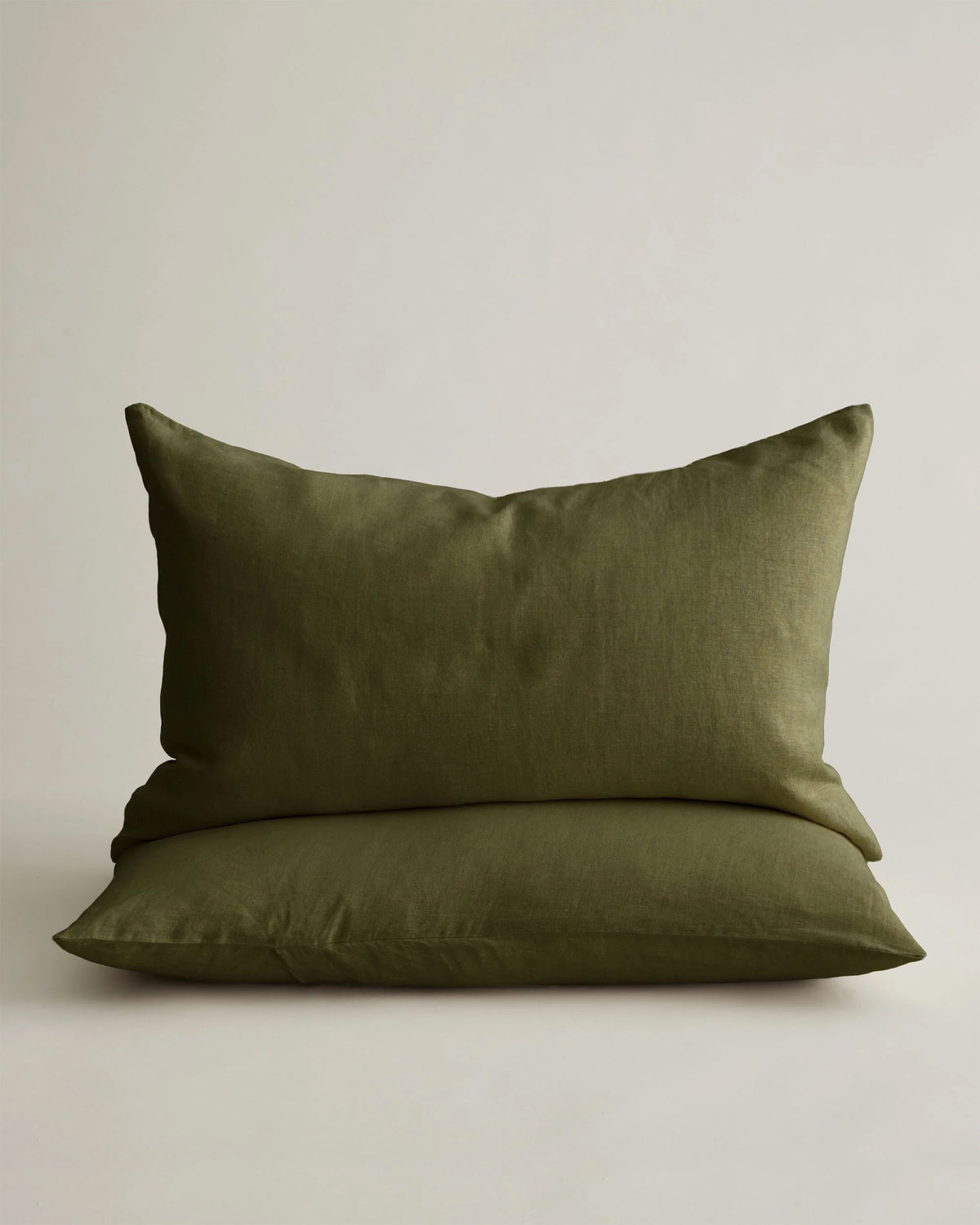 Stacked olive green linen pillowcases by Cultiver Goods USA, shown against a light background.
