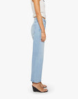 A person wearing The Dodger Ankle jeans by Mother, a sleeveless white top, clear wedge sandals, and gold jewelry stands in profile against a plain white background.