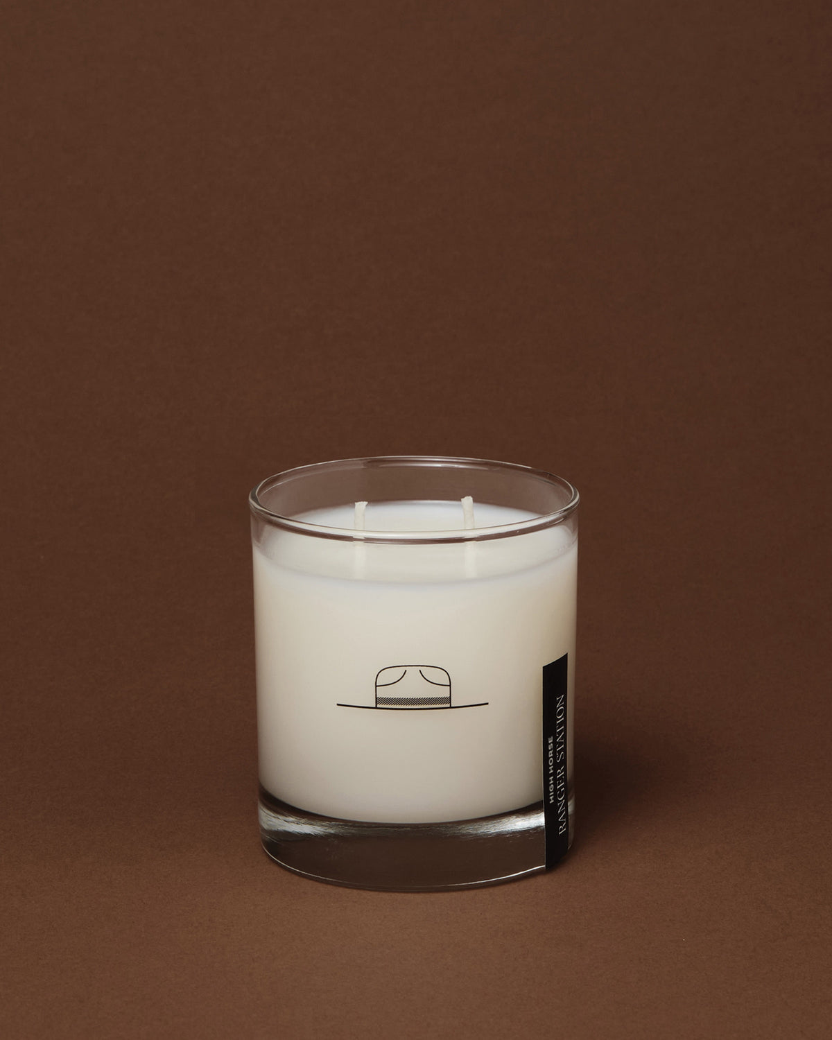 High Horse two-wick soy wax candle in a clear glass jar with a hat logo, set against a dark brown background.