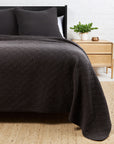 POM POM Huntington Queen coverlet on a bed with pillows, styled beside a nightstand in a cozy bedroom setting.