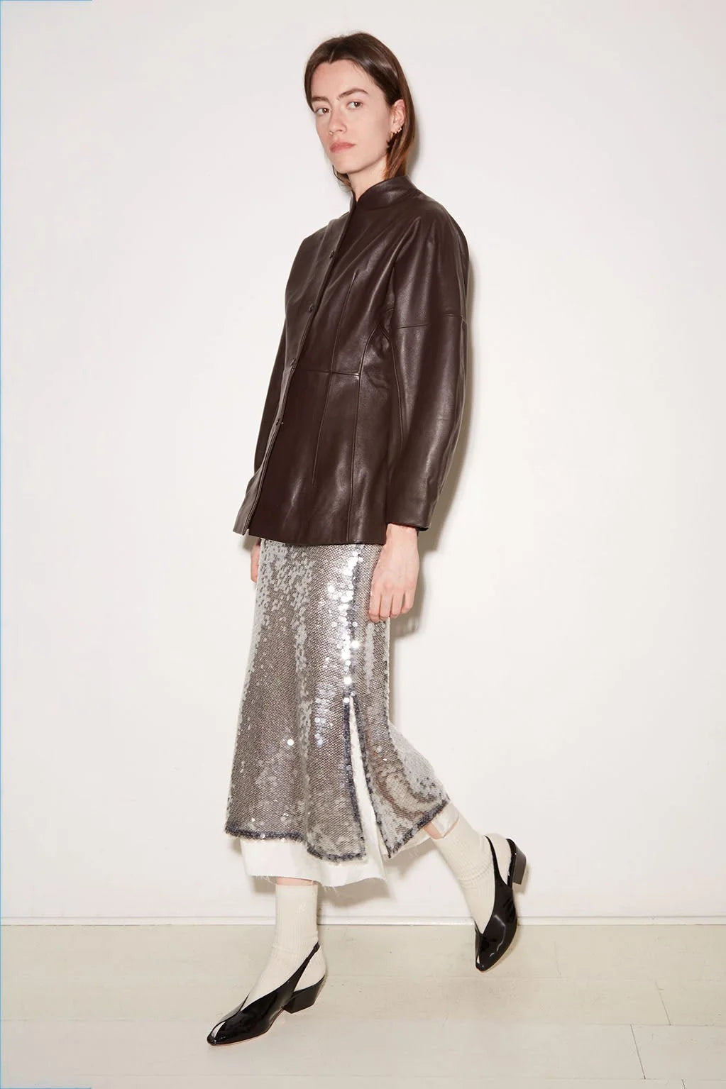 Silver sequined Roseanna Jupe skirt with side slits paired with a dark brown leather jacket.