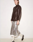 Silver sequined Roseanna Jupe skirt with side slits paired with a dark brown leather jacket.