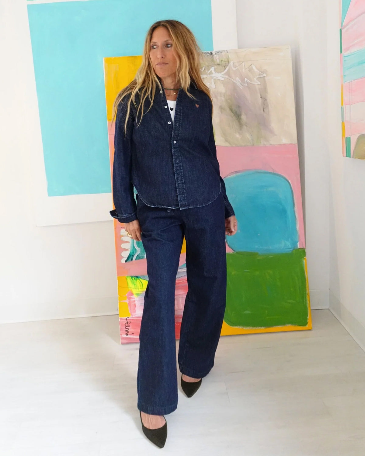 Keaton Denim Shirt by Kerri Rosenthal in a bright, modern room with colorful abstract art and white walls.