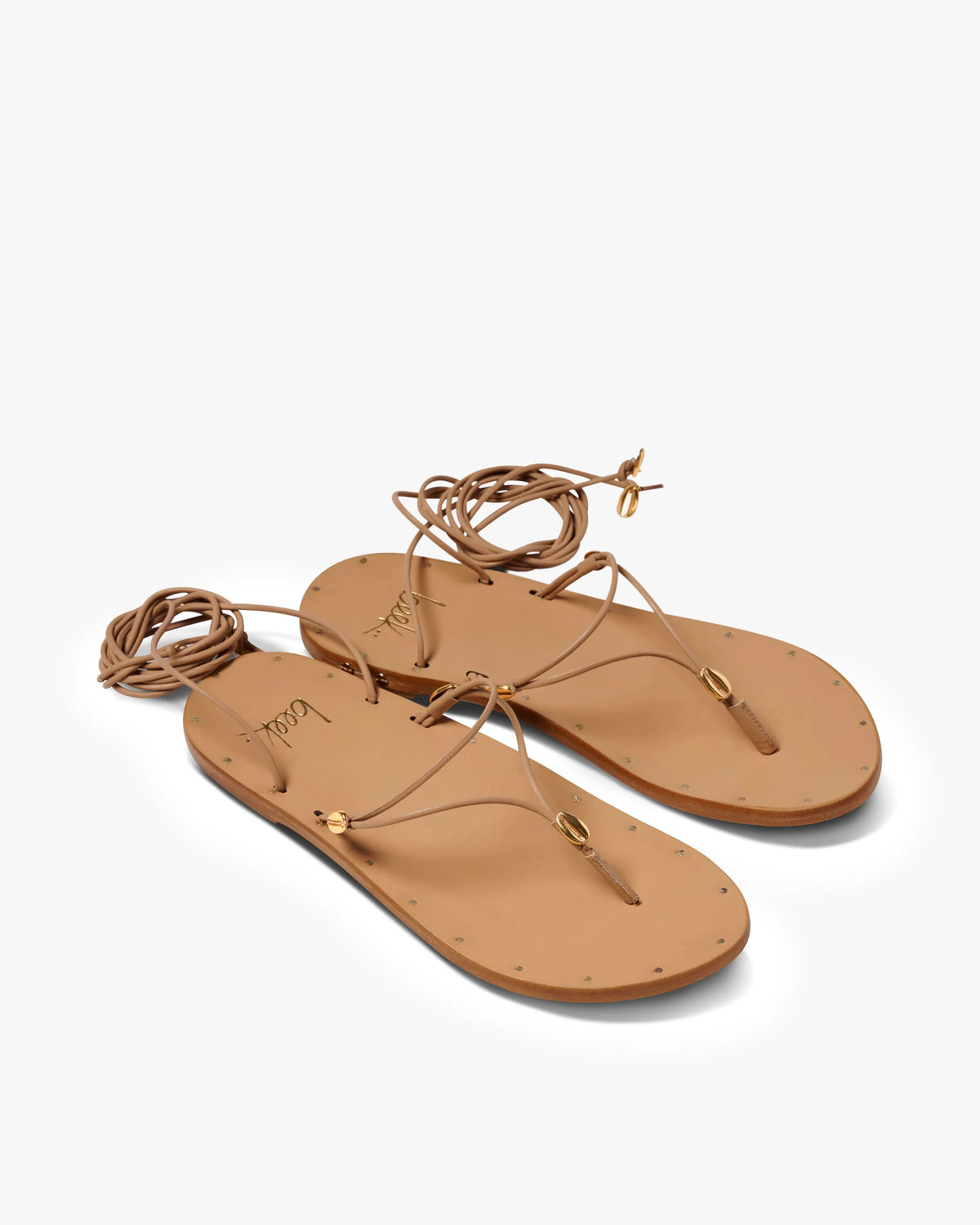 The Beek Koha Sandal features tan leather, molded arch support, thin ankle-wrap straps, and gold-tone hardware, shown against a plain white background.