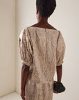 Textured gold Rachel Comey Filly Top with voluminous sleeves, styled with a small black clutch.