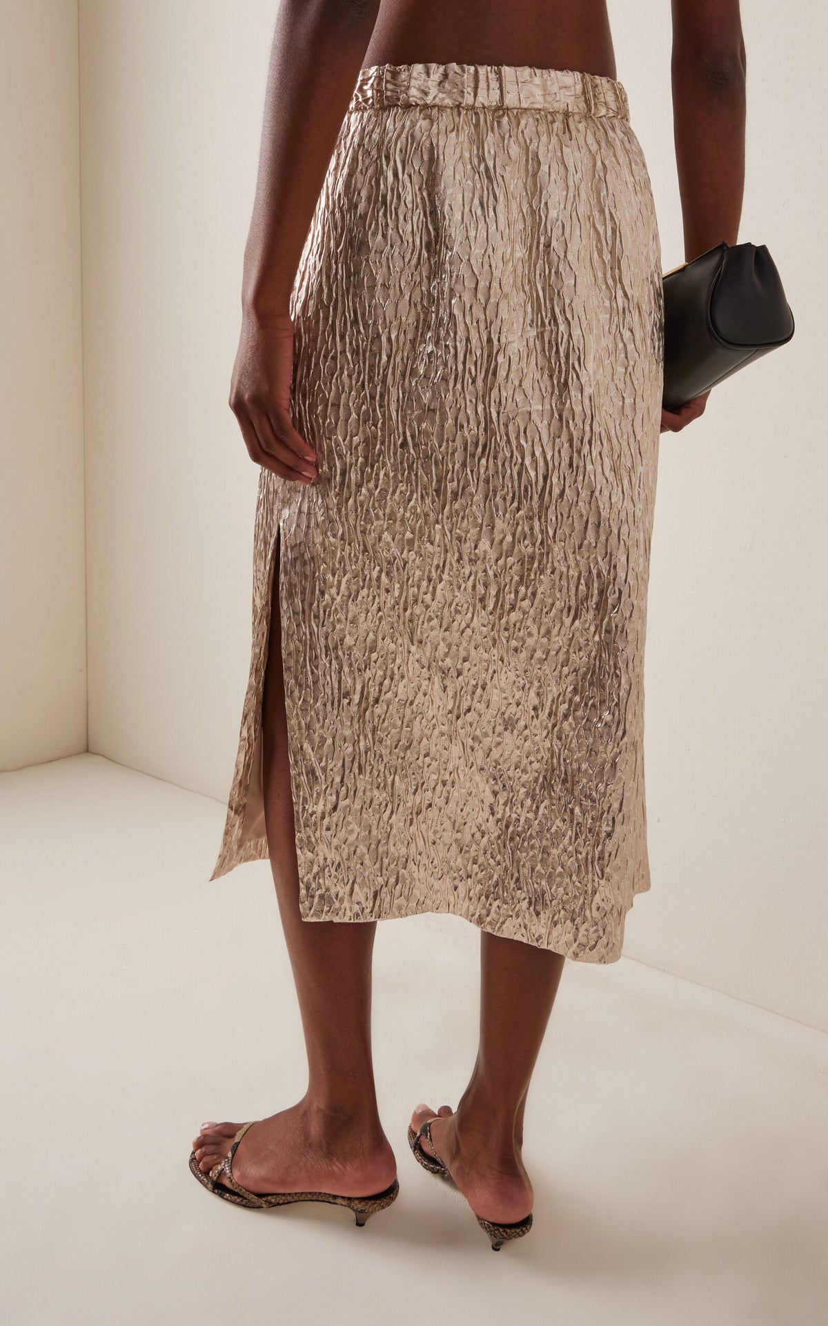 Rachel Comey Mott side-slit skirt styled with a black clutch and open-toe sandals for a modern, chic look.