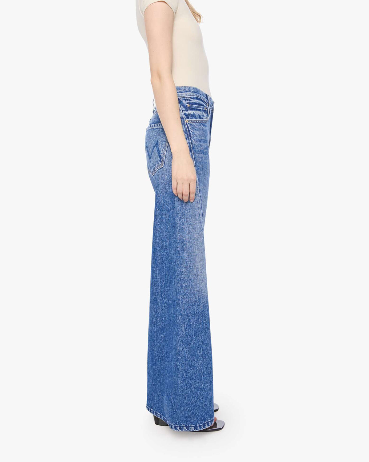 High-waisted Mother Lil Lemon Twist Skimp jeans paired with a beige short-sleeve top, model shown side view.