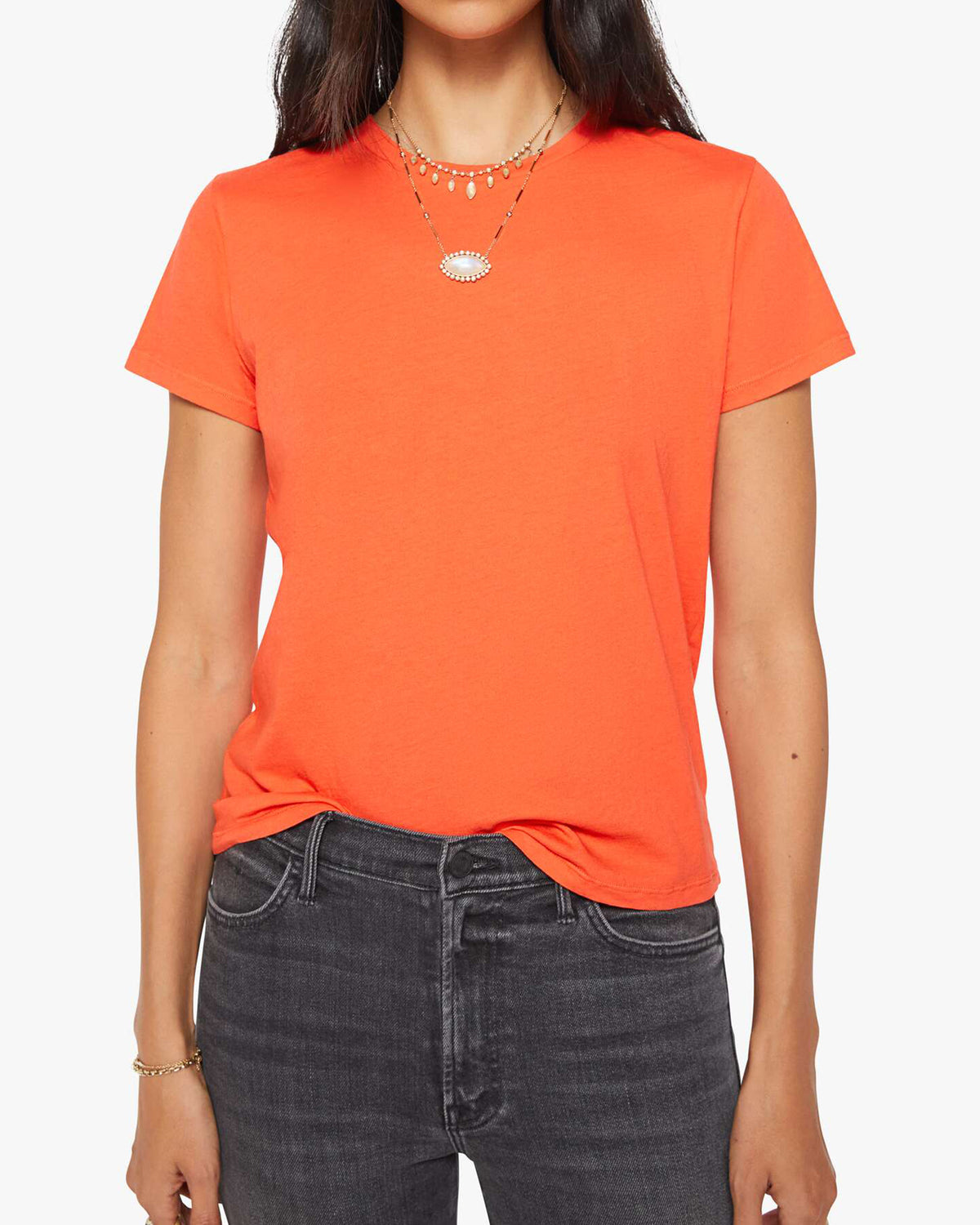 Mandarin red Mother’s The Lil Goodie Goodie Tee styled with layered necklaces and black jeans, front view.