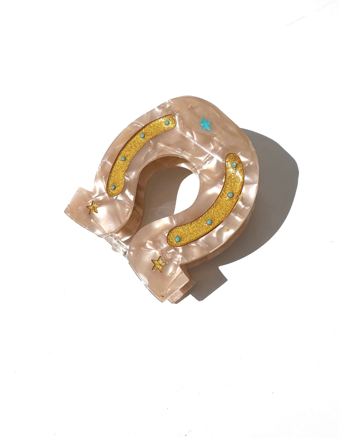 Beige marbled horseshoe hair clip with yellow glitter, blue dots, and stars by Faire, made from biodegradable acetate.
