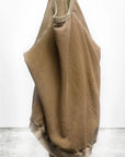 A tan, oversized Lucky Rabbits Sweatshirt by Free City (sparrow, LLC) hangs on a hook against a white wall and concrete floor, featuring lightweight French terry fabric that drapes softly with partially visible sleeves.