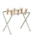 The Maileg Drying rack w. pegs, Miniature is a small, foldable drying rack with a light green metal frame and wooden pegs—ideal for dollhouse laundry scenes.