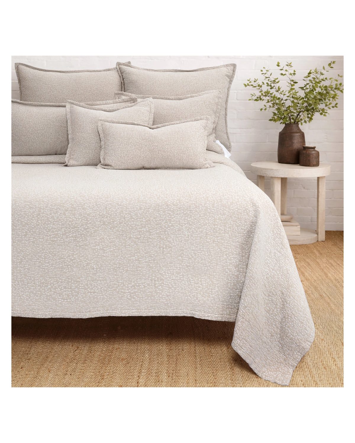 Beige textured bedding with matching pillows and Malibu Matelasse Queen blanket by POM POM in a cozy bedroom.