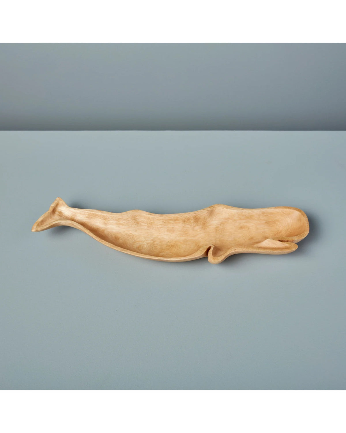 Kiln Mango Wood Whale Dish by Be Home on a smooth light blue surface with matching background.
