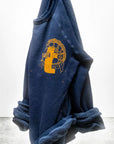 The Artyard SUPERSHOP STAMP Raglan by Free City (sparrow, LLC) is a navy blue unisex sweatshirt with rolled cuffs, made in the USA. It features a large yellow-orange graphic and "thecitycalmbooks yard shop" on the chest.