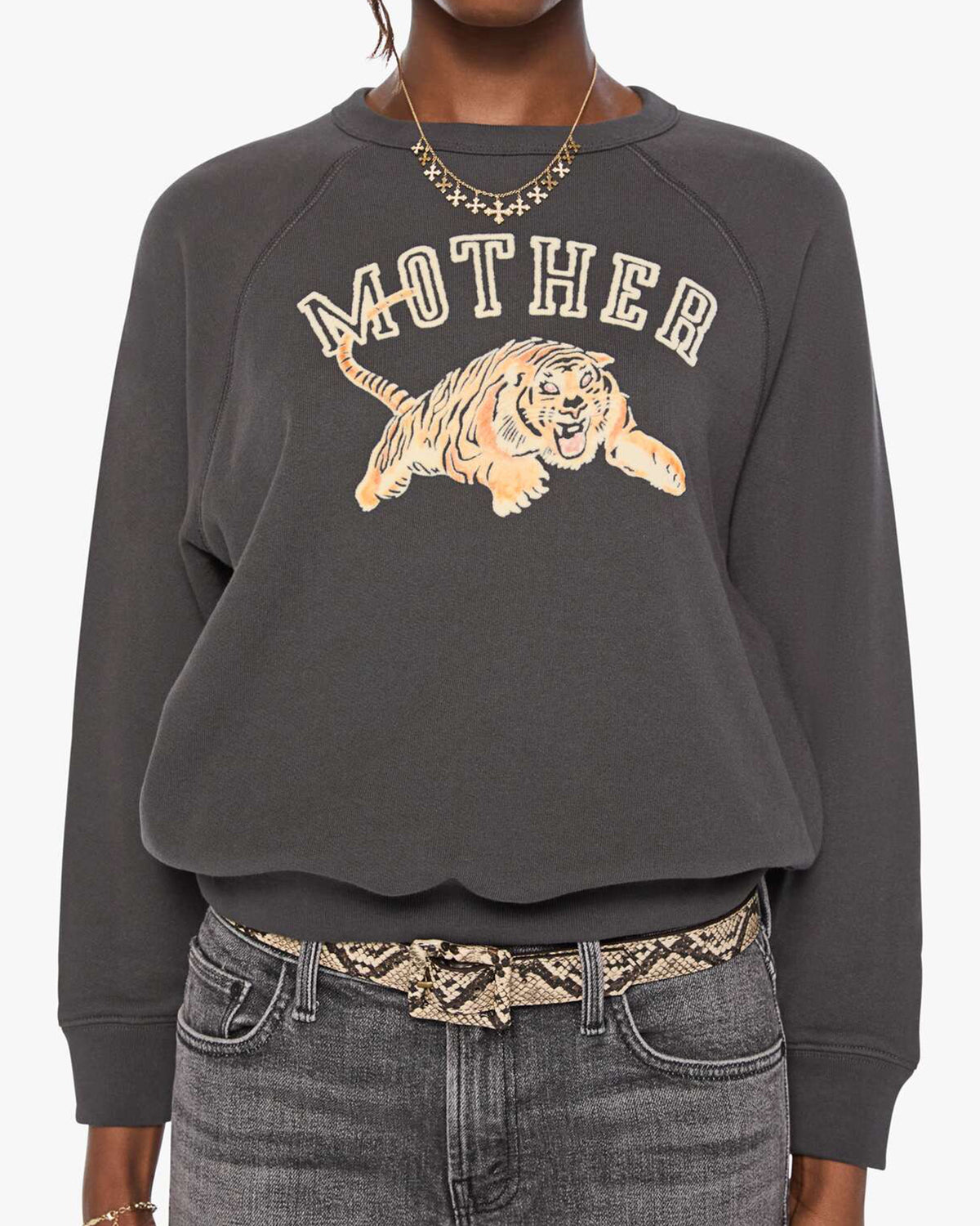 The Concert sweatshirt by Mother paired with cropped jeans and a snake-print belt for a casual, modern look.