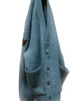 Norwegian Blue SuperYumm wool pocket cardigan with two pockets and a dark upper sleeve graphic.