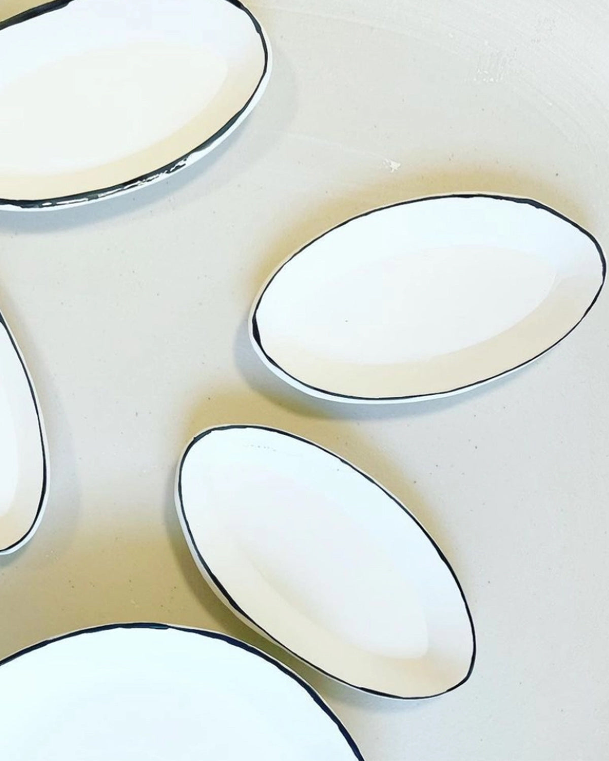 Oval trays with thin black rims from Bungalow Furniture arranged on a light background in a minimal style.