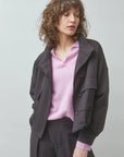 Pink sweater layered with oversized brown jacket and matching pants from SUNCOO, styled in a simple studio setting.