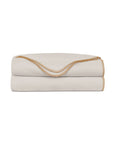 Beige coverlet with brown blanket stitching by Eastern Accents, folded on Carrara Fog surface at Bungalow Furniture.