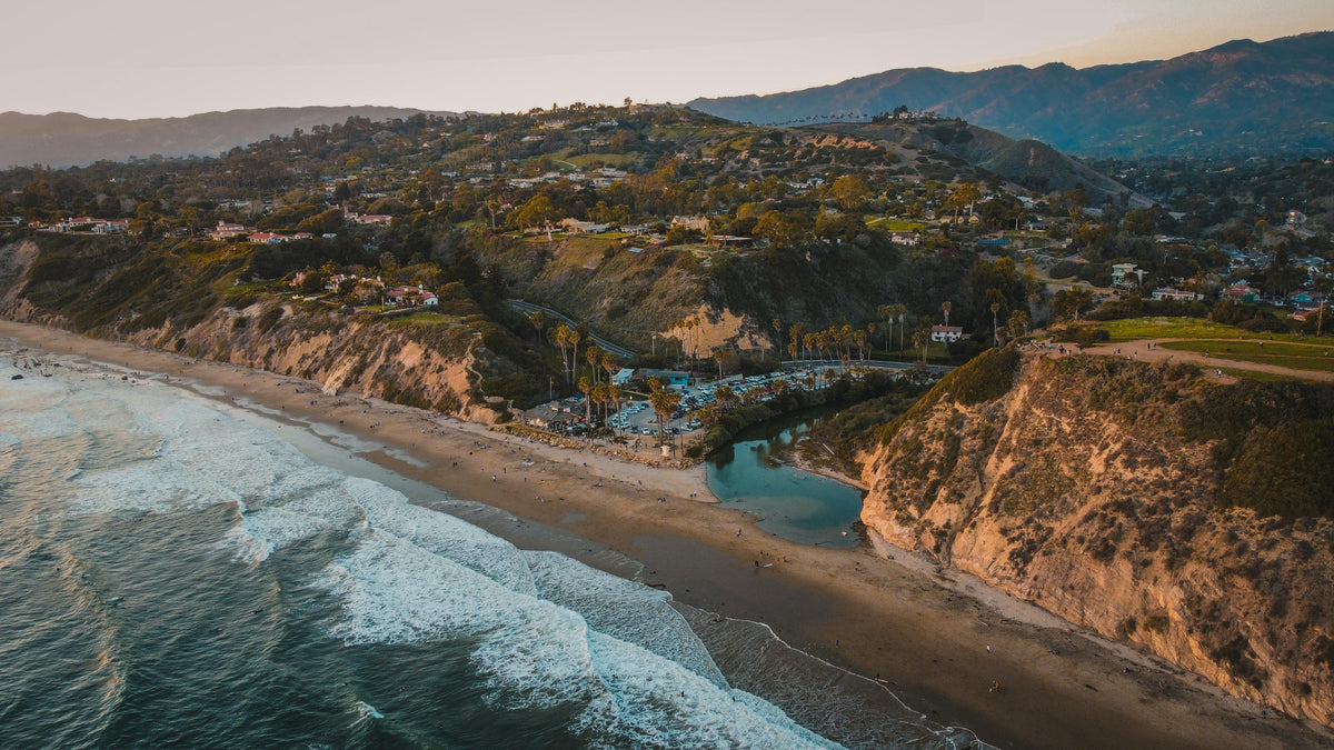 Coastal chic setting with beachside bungalows, cliffs, and ocean waves at sunset—relaxed living inspiration.