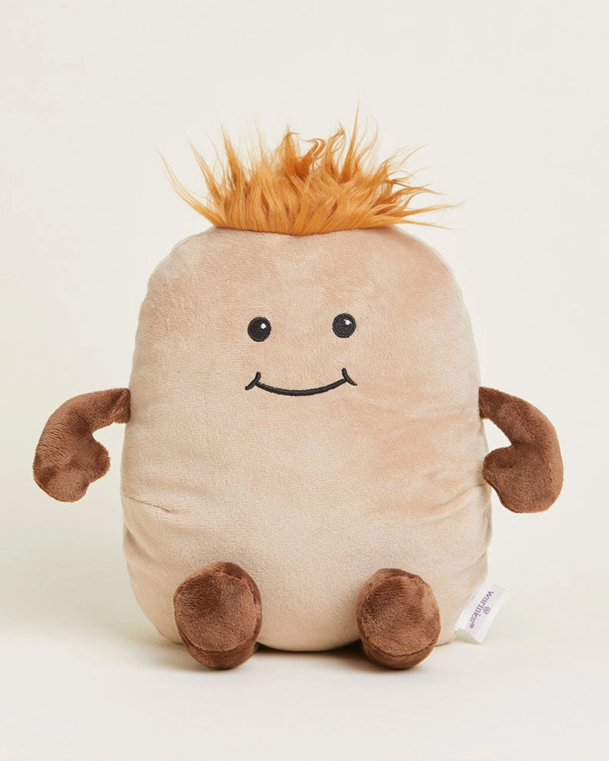 The Faire Potato Warmies is a microwavable plush shaped like a smiling light brown potato with brown limbs and orange spiky hair, offering cozy sensory comfort as it sits upright against a plain background.
