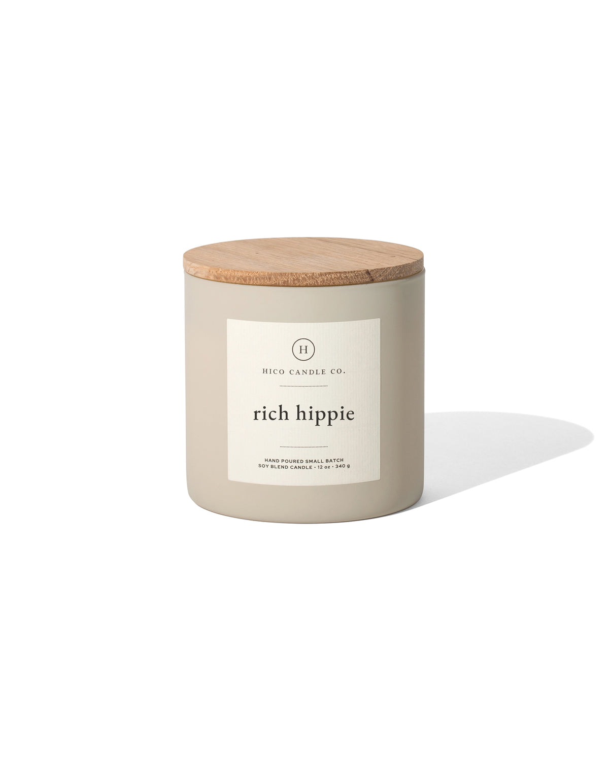 A Faire "Rich Hippie" 14oz. beige soy wax candle jar with a wooden lid rests on a white background, casting a soft shadow to the right.