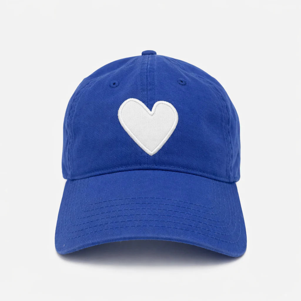 The KR Imperfect Heart Hat by Kerri Rosenthal is a royal blue baseball cap with a white embroidered heart patch on the front, shown against a plain white background.
