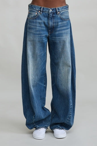 Denimist Remy Barrel Jean in relaxed mid-rise blue denim, styled with white sneakers on a light background.