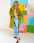 Sienna Duster by Kerri Rosenthal in olive worn over a white top and cuffed blue jeans.