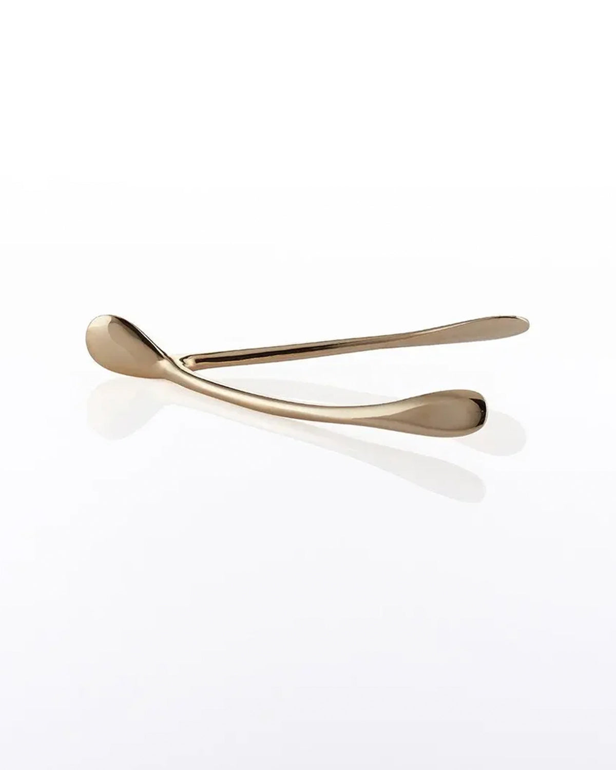 A metallic gold Wishbone /Small decor piece rests on a glossy white surface, casting a soft reflection—an elegant handcrafted aluminum accent.