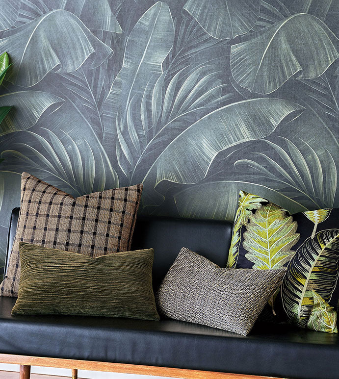 Bungalow Furniture &amp; Accessories Beachcomer Check Pillow 22x22 on a black leather sofa with dark tropical wallpaper.