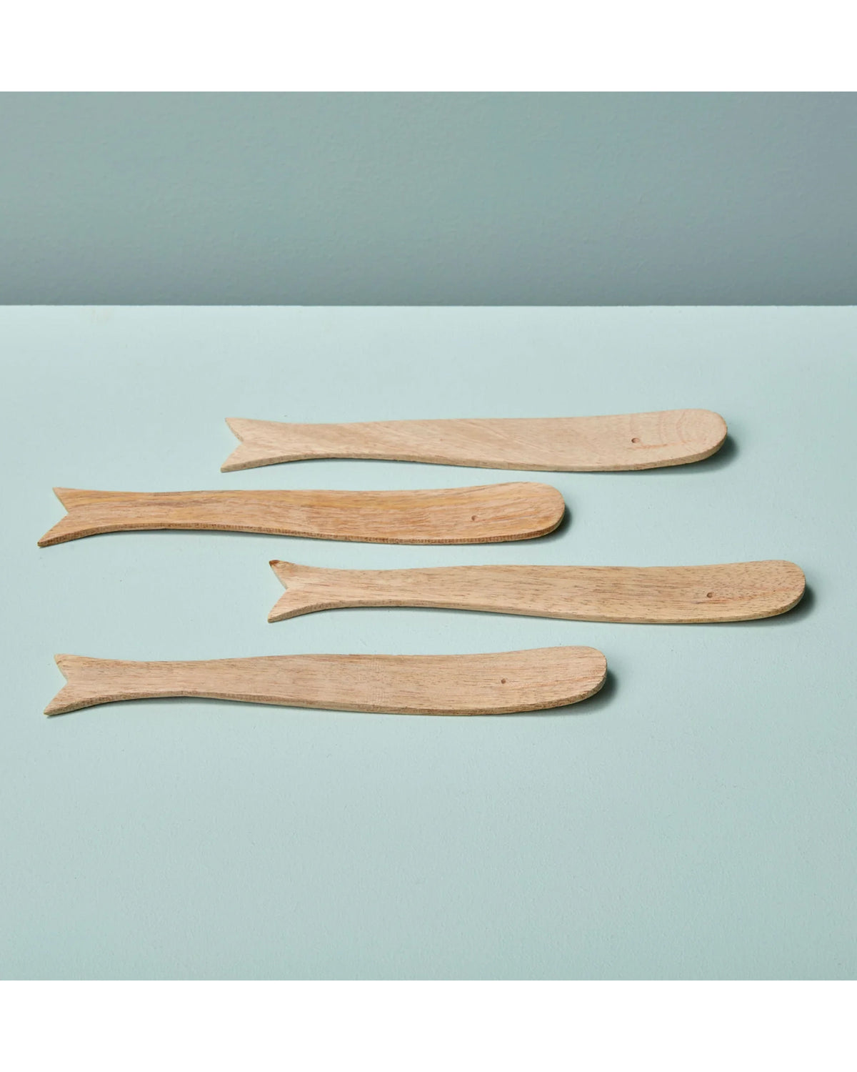 Four whale-shaped mango wood spreaders by Be Home on a light blue surface, playful serveware for kitchen or dining.