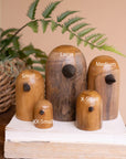 Set of Kalalou teak wood bird sculptures displayed on a book with natural decor in a cozy, organic setting.