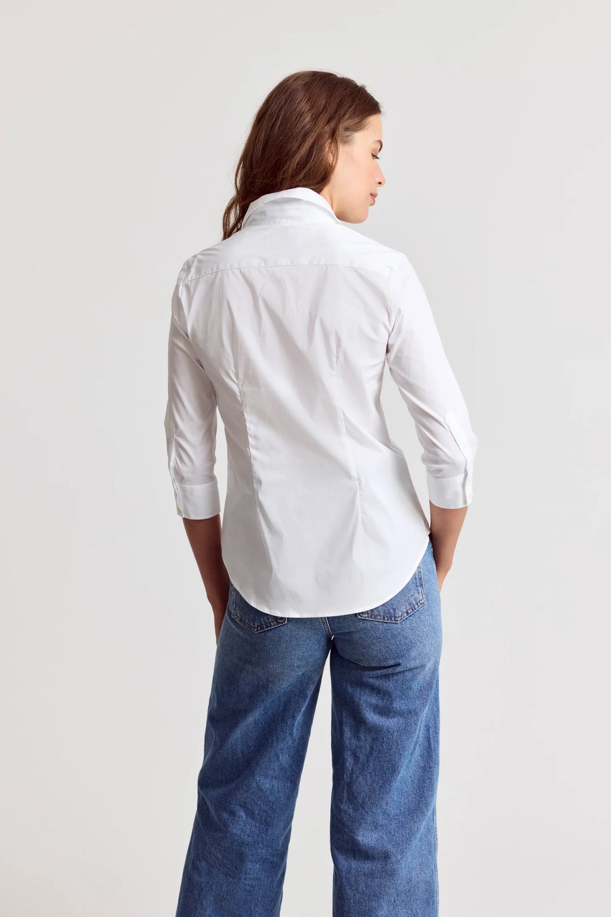 3/4 sleeve Essentials Icon Shirt by THE SHIRT in white, styled with blue jeans, model shown from the back.
