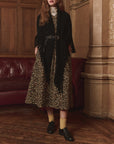 Leopard print dress with The Great Inc. Big Sweater Fringe Scarf, styled in an elegant, ornate room by a red couch.