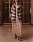 The Car Coat in Chocolate Cream Check by The Great Inc. styled over a polka dot dress near ornate gates.