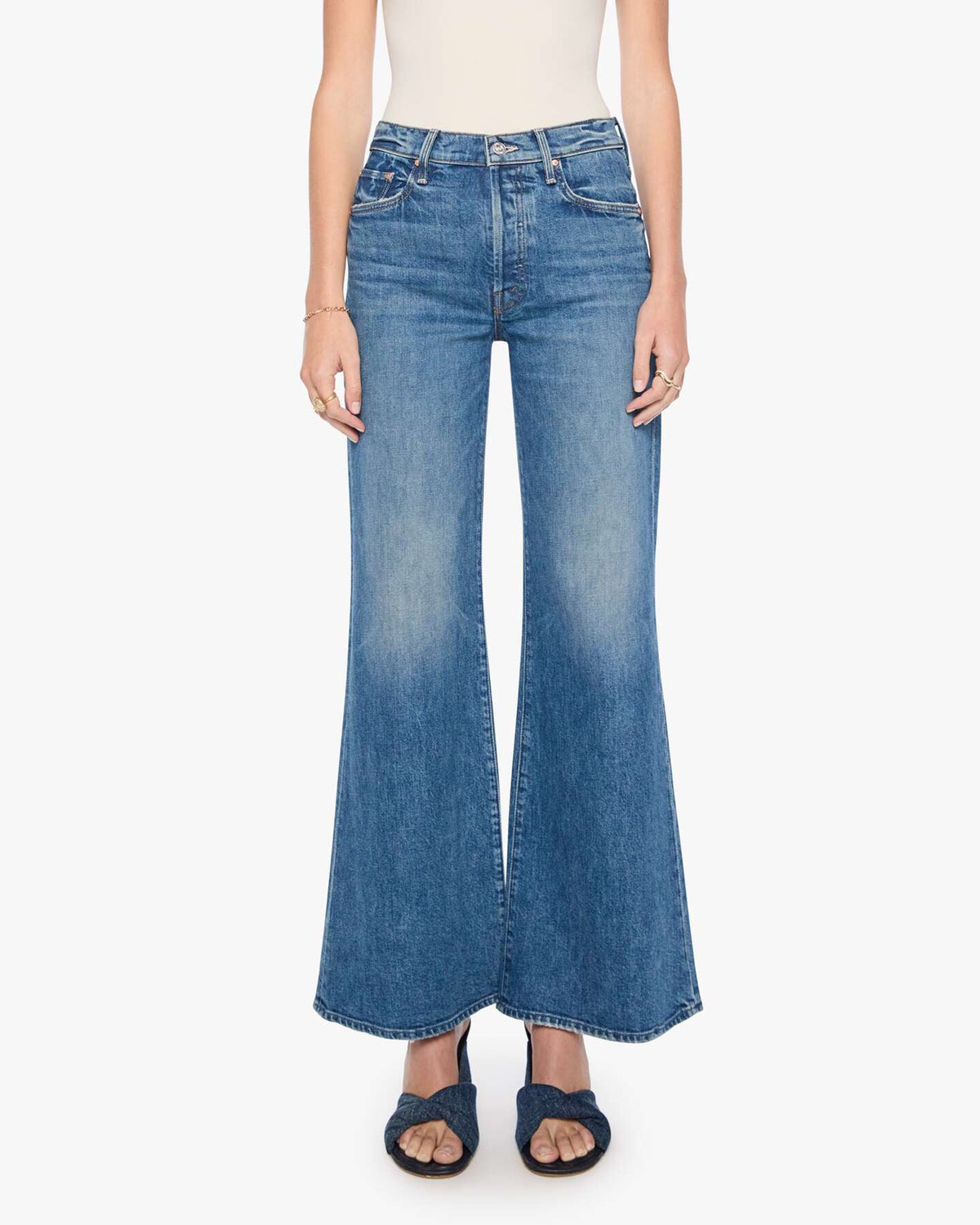 The Tomcat Roller Sneak jeans by Mother styled with a white top and black sandals for a vintage denim look.