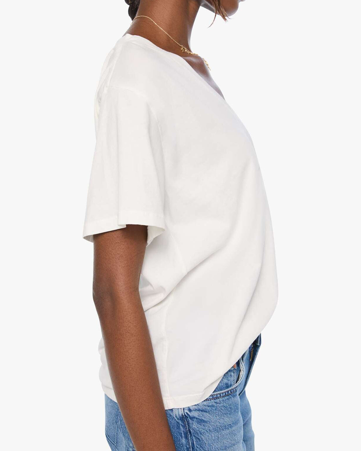 The Varsity Rowdy sweater by Mother, ivory with blue trim, styled with blue jeans, side view on white background.