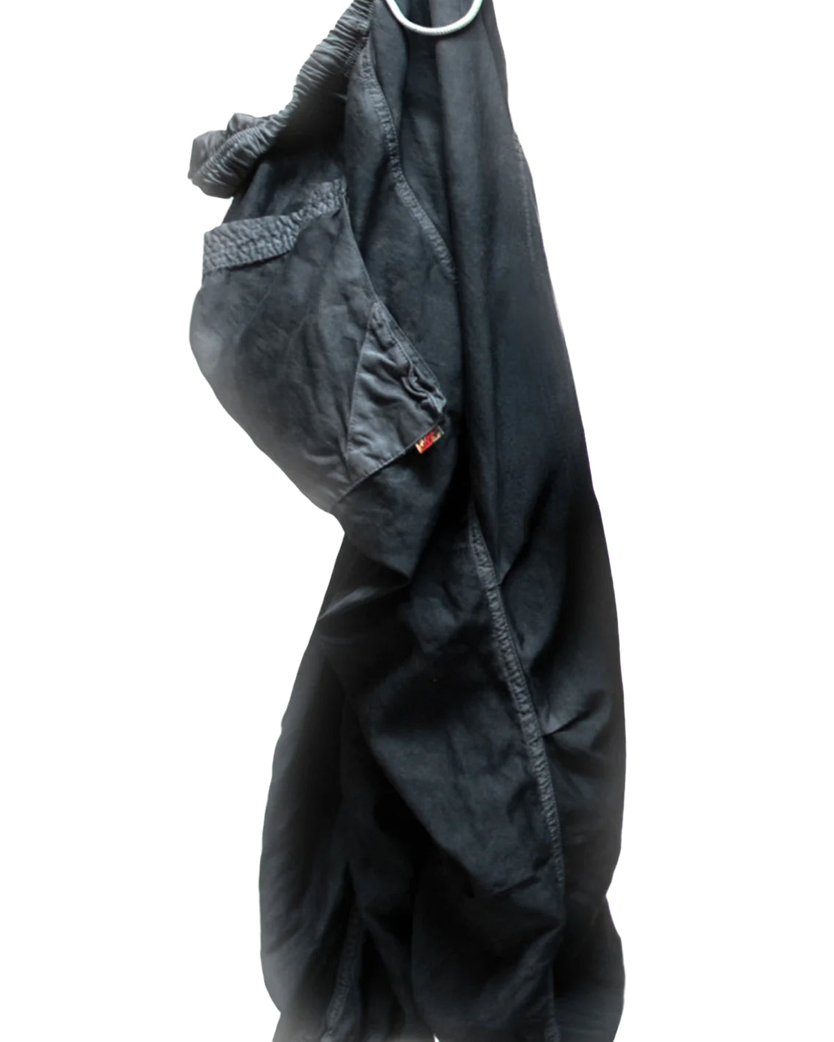 A pair of oversized Matte/Satin Biggy Pants by Free City (sparrow, LLC) in black hangs from a metal ring against a white background, with one leg tucked inside out.